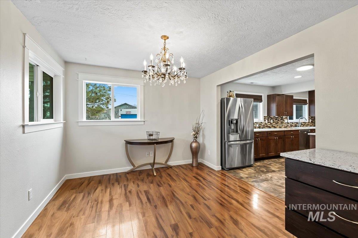 11545 Kuna Road Kuna, ID 83634 - Photo 7 of 50 Dining room featuring a chandelier, dark wood finished floors, healthy amount of natural light, and a textured ceiling