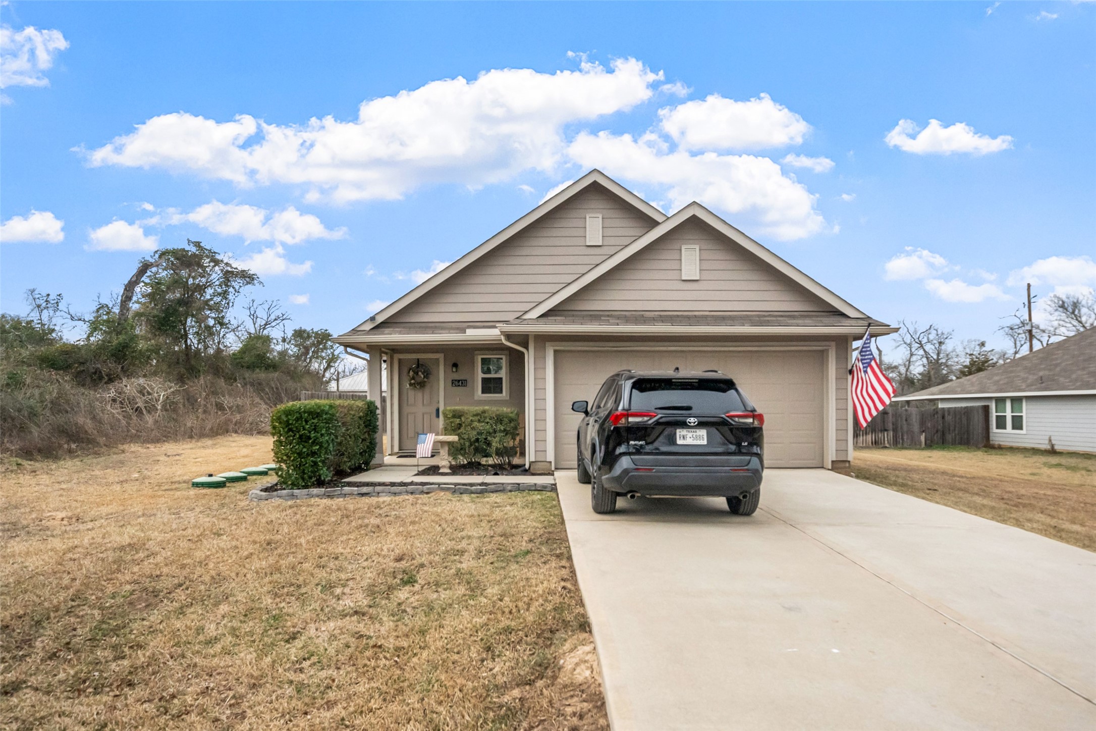 26431 Pin Oak Drive Hempstead, TX 77445 - Photo 7 of 32 Inviting front exterior with extended driveway parking and an attached 2-car garage. Neutral tones and a tidy landscape create a clean, well-maintained look.