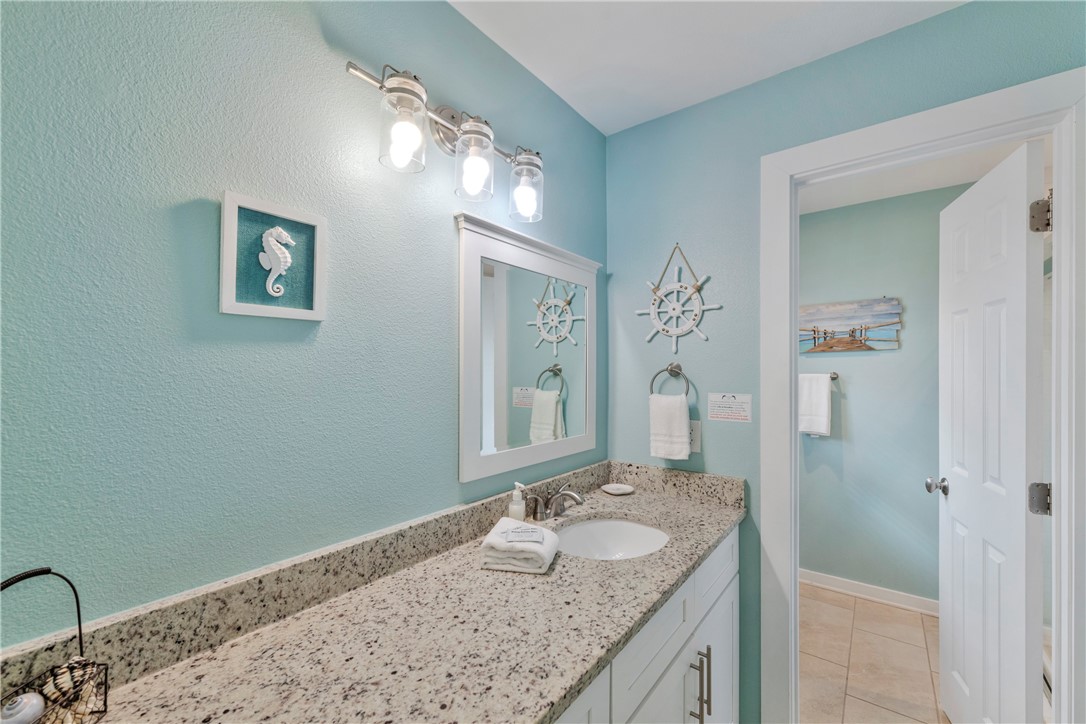 230 Cut-Off Road, Unit 205 Port Aransas, TX 78373 - Photo 23 of 37 a bathroom with a granite countertop sink a mirror and shower