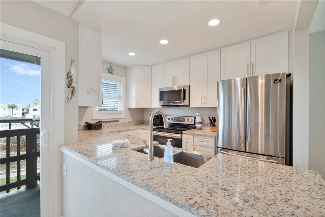 230 Cut-Off Road, Unit 205 Port Aransas, TX 78373 - Photo 10 of 37 a kitchen with stainless steel appliances granite countertop a refrigerator stove microwave and sink