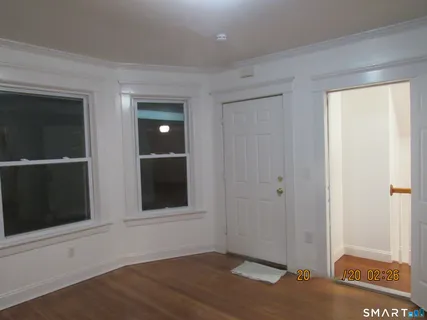 a view of an empty room with wooden floor and a window