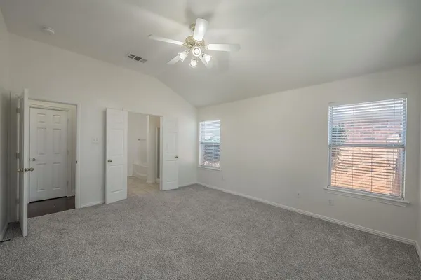 an empty room with chandelier fan and windows