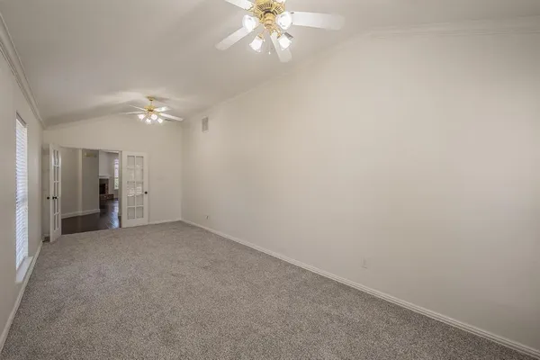 an empty room with chandelier fan and closet area
