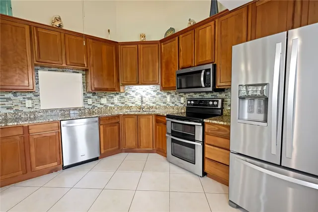 a kitchen with granite countertop a refrigerator stove top oven and sink