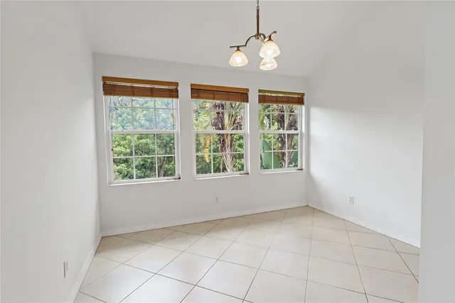 an empty room with chandelier fan and windows