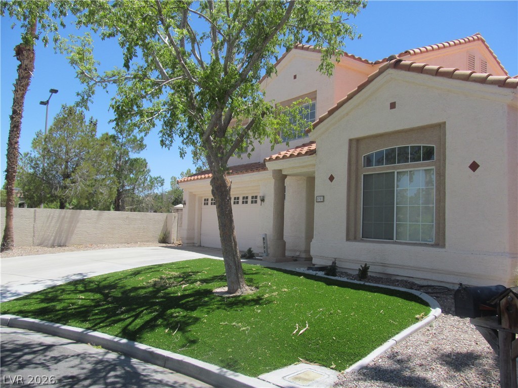 8701 Crescent Ridge Lane Las Vegas, NV 89134 - Photo 2 of 28 A well-kept front yard offers low-maintenance artificial turf alongside a spacious driveway.
