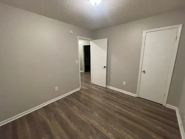 a view of a hallway with wooden floor and a bathroom