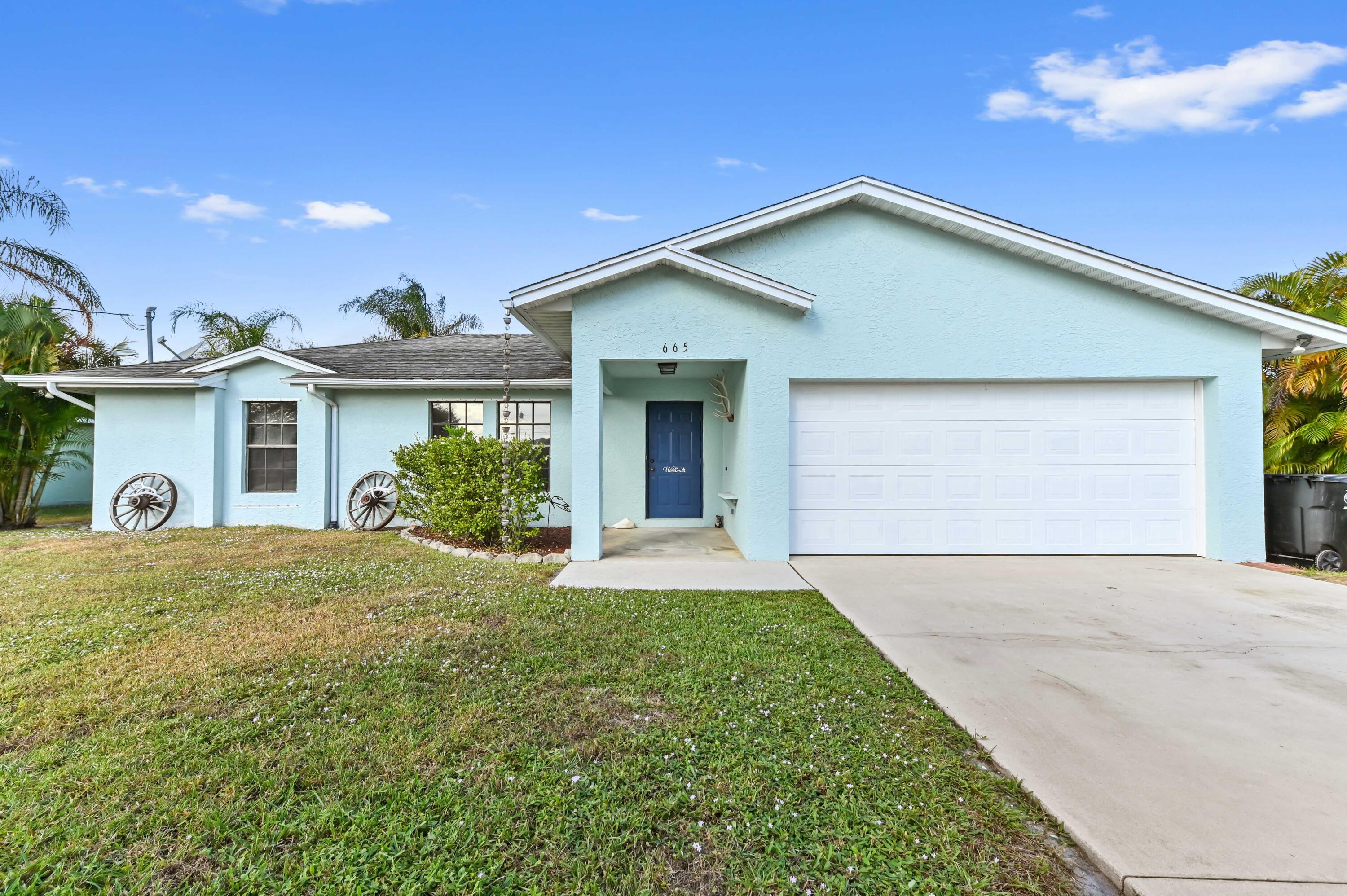 665 Southwest Backert Avenue Port St. Lucie, FL 34953 - Photo 1 of 46 a front view of a house with a yard and garage