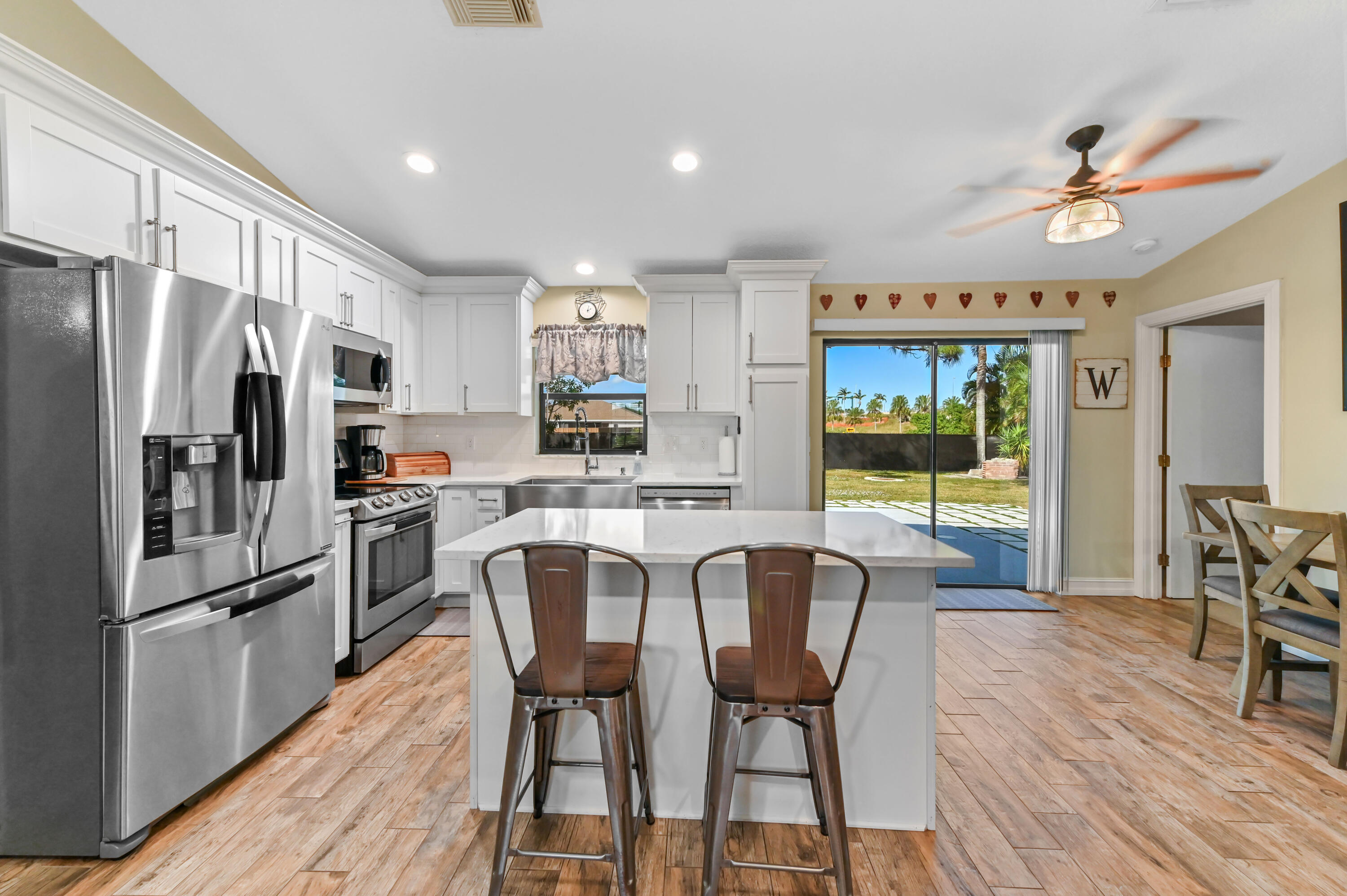 665 Southwest Backert Avenue Port St. Lucie, FL 34953 - Photo 13 of 46 a kitchen with stainless steel appliances a refrigerator a stove a dining table and chairs with wooden floor