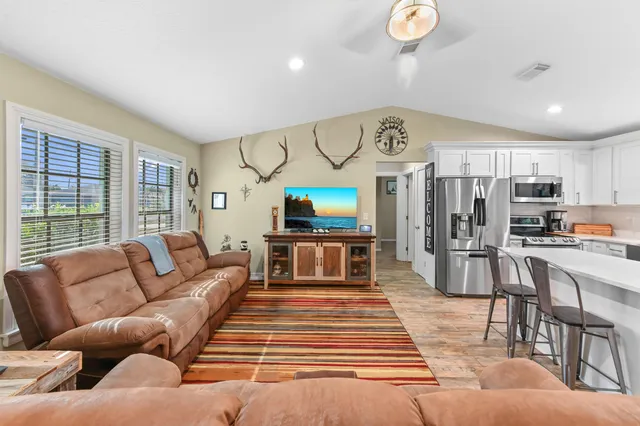 a open kitchen with stainless steel appliances granite countertop a stove top oven a sink dishwasher a dining table and chairs with wooden floor