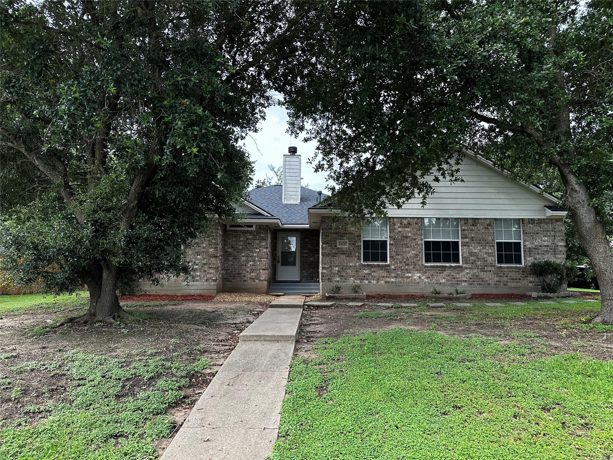1400 Prairie Drive Bryan, TX 77802 - Photo 2 of 18 Mature trees shade this charming brick home with a welcoming front pathway and tidy landscaping.