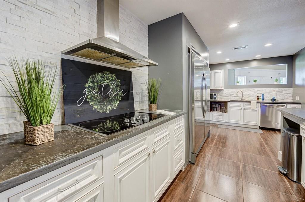 10213 Stewart Road Galveston, TX 77554 - Photo 20 of 49 a kitchen with stainless steel appliances kitchen island granite countertop a refrigerator a stove a sink and white cabinets