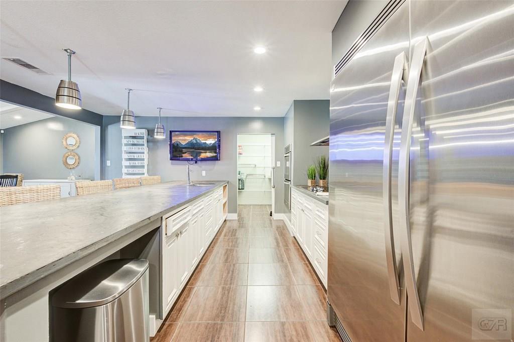 10213 Stewart Road Galveston, TX 77554 - Photo 24 of 49 a large kitchen with a large counter top a refrigerator and cabinets
