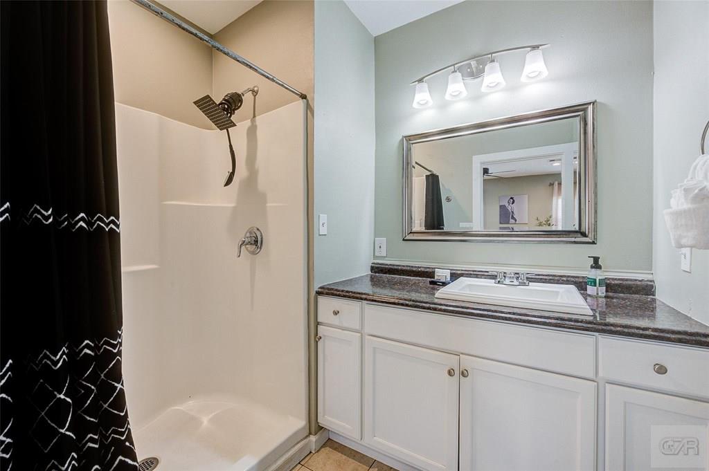 10213 Stewart Road Galveston, TX 77554 - Photo 29 of 49 a bathroom with a granite countertop sink a mirror a vanity and a shower