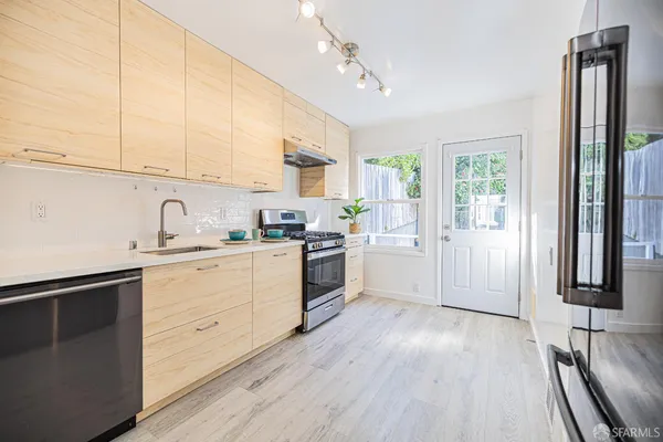 a kitchen with granite countertop a stove a sink and a refrigerator
