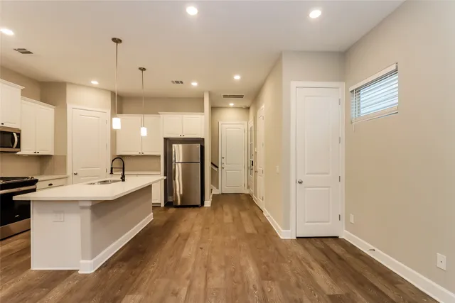 a kitchen with granite countertop a sink stainless steel appliances and white cabinets
