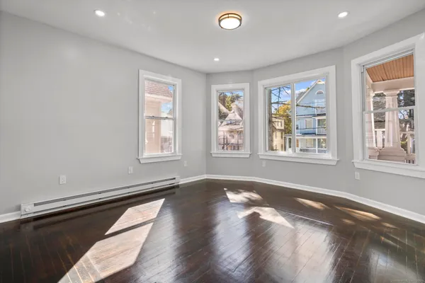 a view of an empty room with a window and wooden floor