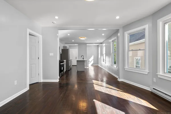 a view of a hallway with wooden floor windows and a kitchen