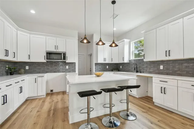 a kitchen with stainless steel appliances granite countertop a stove a sink dishwasher a microwave oven with white cabinets and wooden floor