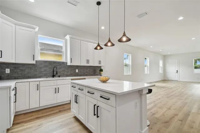 a kitchen with stainless steel appliances granite countertop cabinets a sink a window and chairs