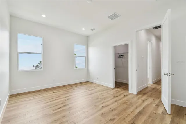 a view of an empty room with wooden floor and closet