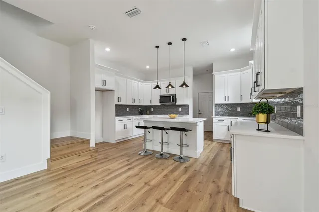 a kitchen with kitchen island a stove a sink a refrigerator and white cabinets with wooden floor