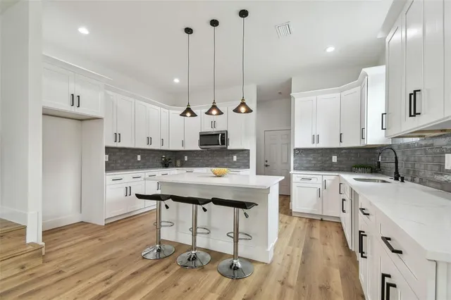 a kitchen with a stove a refrigerator a sink dishwasher and white cabinets with wooden floor