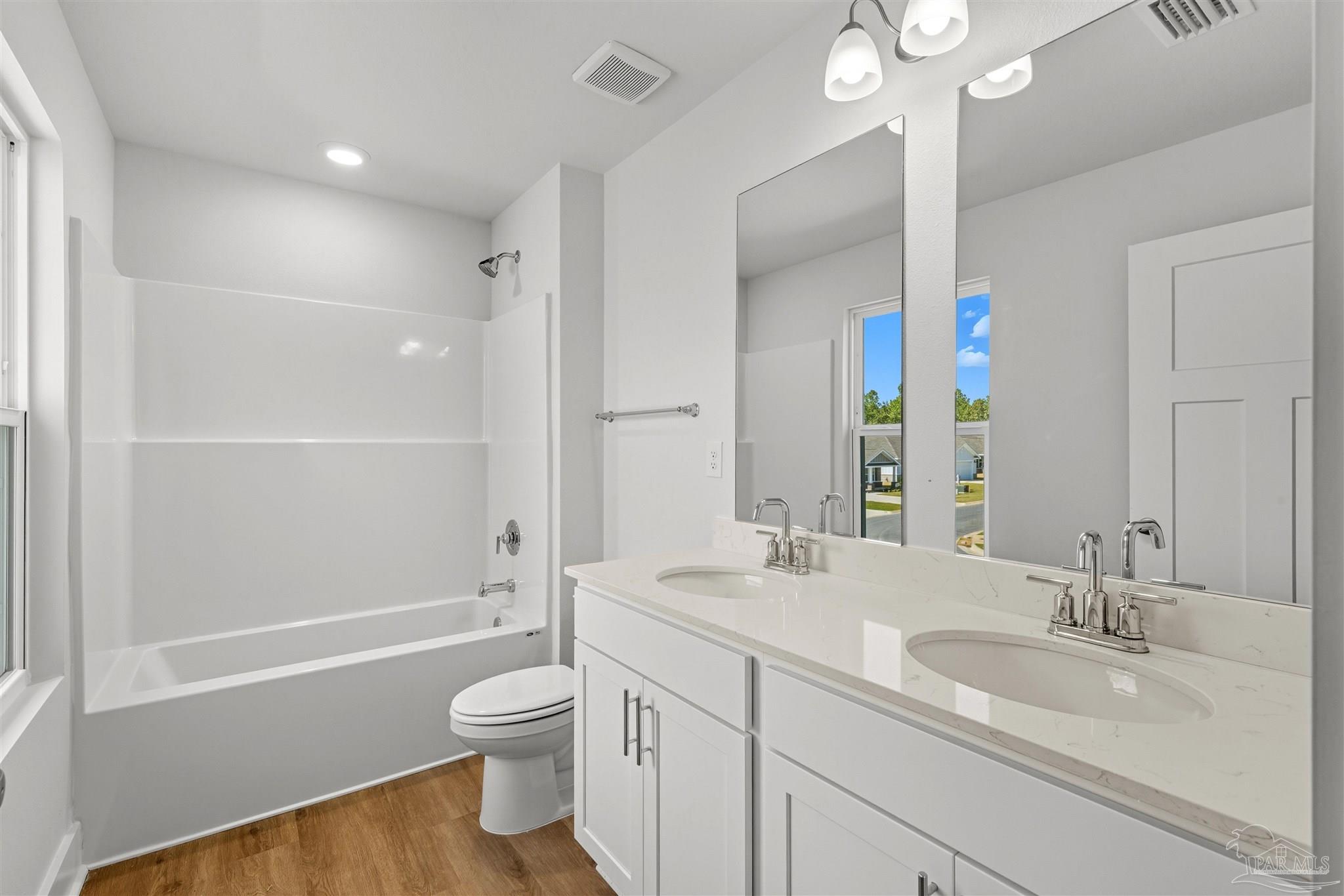 3162 Serviceberry Road Cantonment, FL 32533 - Photo 29 of 35 a bathroom with a granite countertop sink toilet a large mirror a shower and a bathtub