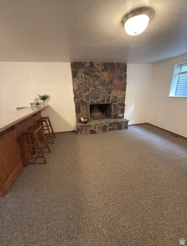 1164 East Mountain Road Logan, UT 84321 - Photo 45 of 52 Stone-clad fireplace with hearth, complemented by a wood-paneled bar featuring a light-toned countertop