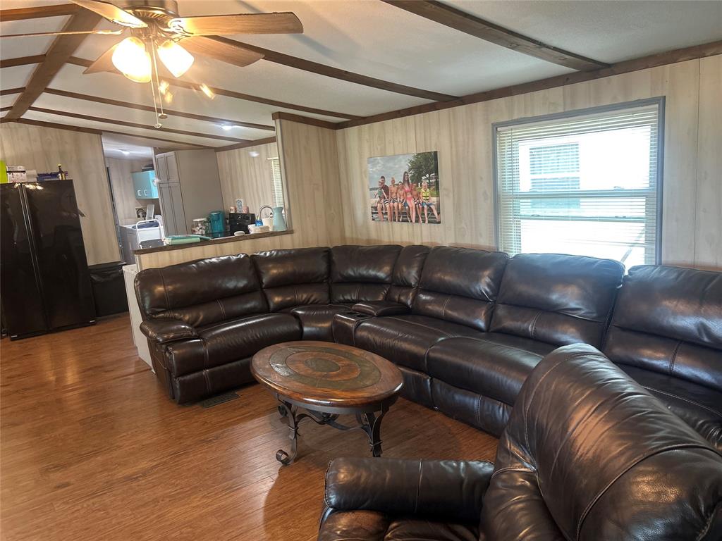 4705 Fox Hollow Road Graham, TX 76450 - Photo 26 of 28 Living room with wood finished floors, beamed ceiling, wooden walls, and a ceiling fan