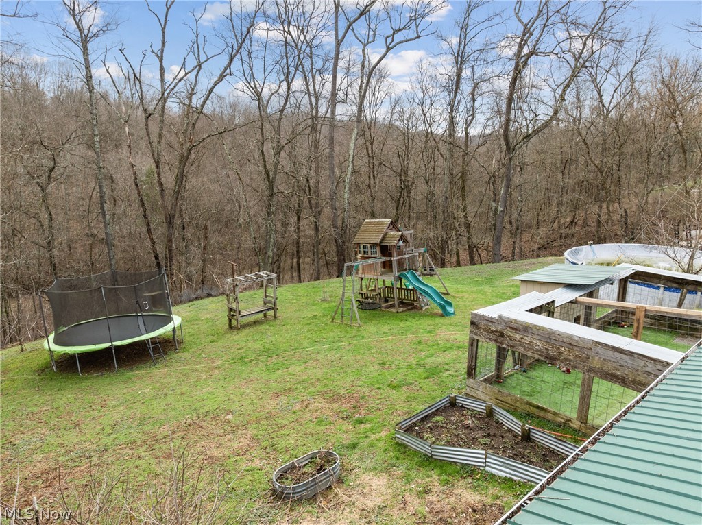 38340 Lees Run Road Cadiz, OH 43907 - Photo 23 of 31 View of green lawn featuring a playground, a trampoline, a vegetable garden, and an outdoor fire pit