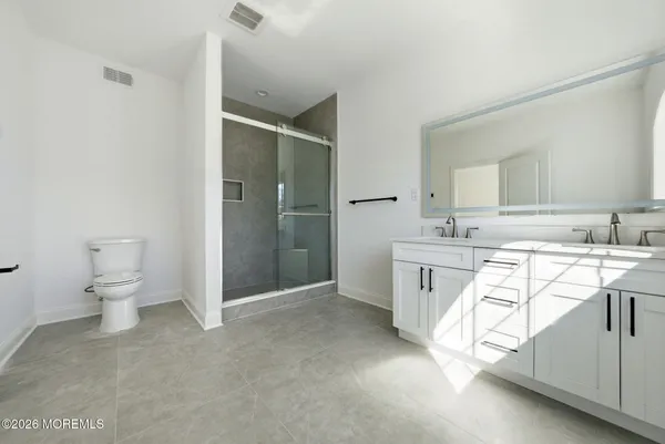 a spacious bathroom with a double vanity sink a mirror and a toilet