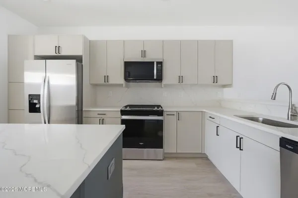 a kitchen with stainless steel appliances a sink dishwasher a refrigerator and cabinets