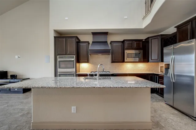 a kitchen with stainless steel appliances granite countertop a refrigerator and a stove