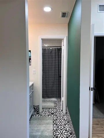 a view of a hallway with wooden floor and a bathroom