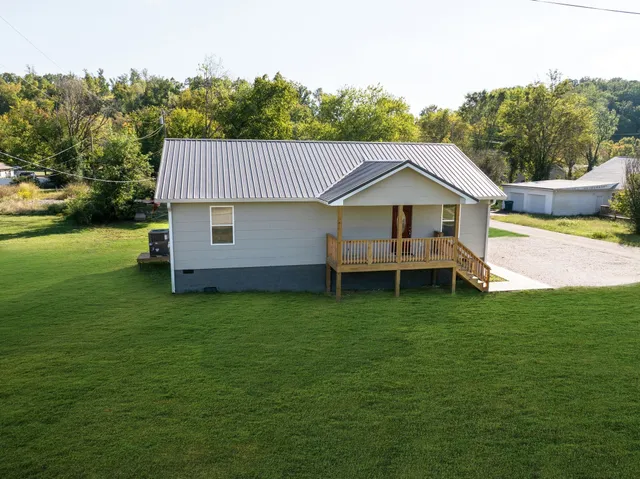 a view of an house with backyard and a tree