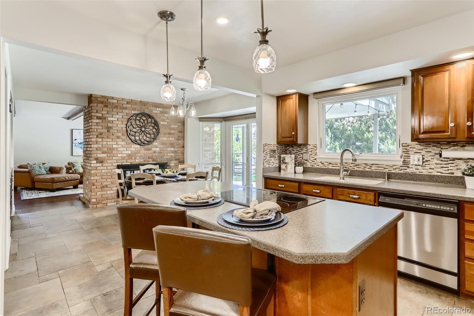 2185 Thistle Ridge Circle Highlands Ranch, CO 80126 - Photo 12 of 37 a kitchen with a stove a kitchen island a dining table and chairs with wooden floor