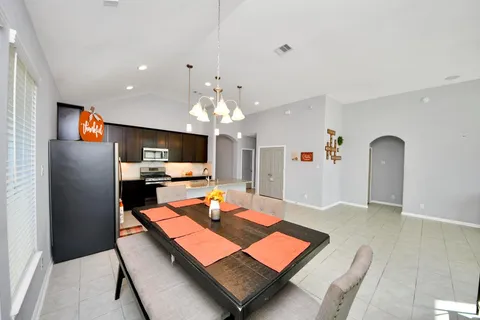 a living room with furniture a flat screen tv and kitchen view