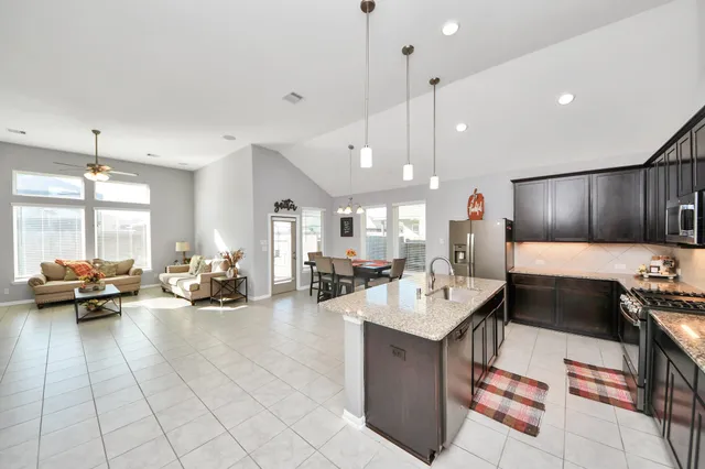 a large kitchen with kitchen island a large counter space a sink stainless steel appliances and cabinets