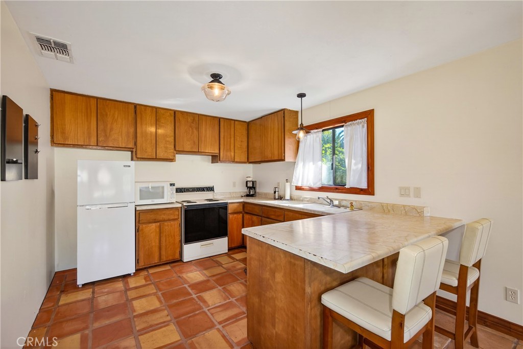 707 Wabash Avenue Redlands, CA 92374 - Photo 38 of 50 a kitchen with a sink a stove a refrigerator cabinets and a dining table