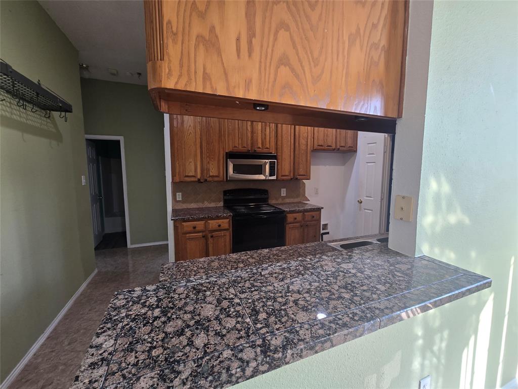 8012 Ashridge Road Fort Worth, TX 76134 - Photo 10 of 18 a kitchen with granite countertop a stove and a microwave