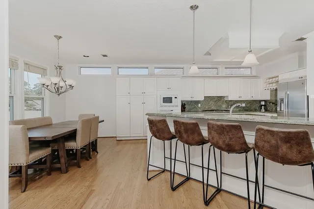 a kitchen with stainless steel appliances kitchen island granite countertop a table chairs in it and white cabinets