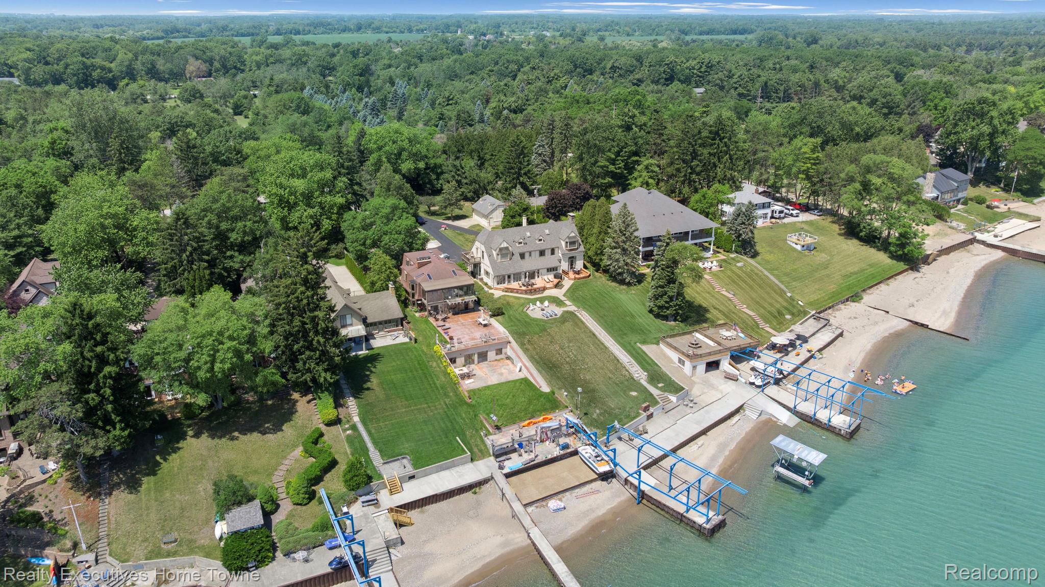 8308 Lakeshore Road Fort Gratiot, MI 48059 - Photo 29 of 79 Waterfront property featuring extensive private frontage, multiple boat hoists, a concrete dock, sloped lawn areas, and mature trees