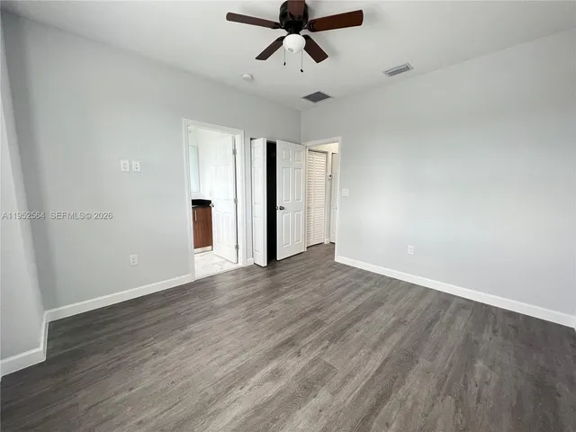 an empty room with wooden floor and ceiling fan