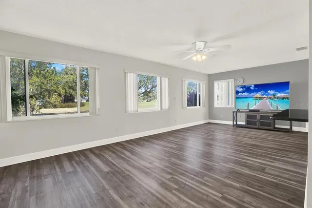 a view of a livingroom with wooden floor window and a ceiling fan