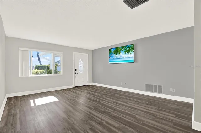 an empty room with wooden floor and window