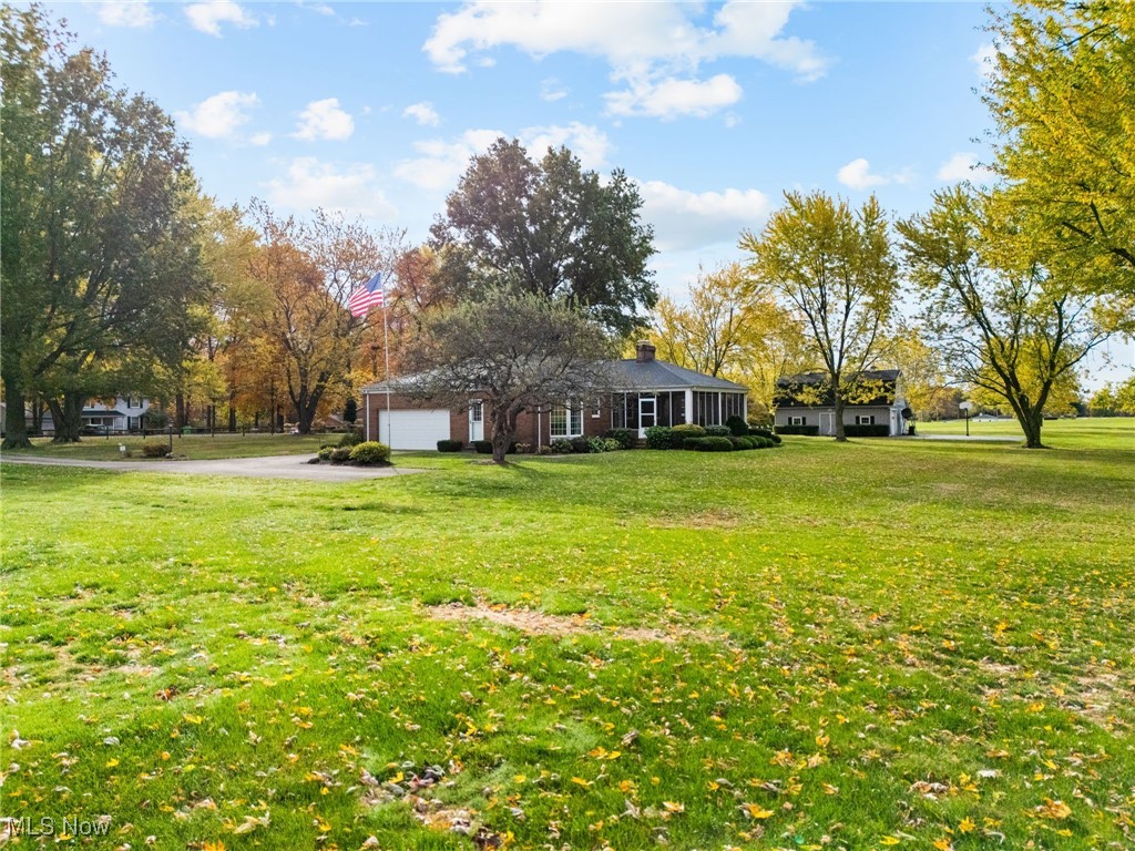 14265 Reeder Avenue Northeast Alliance, OH 44601 - Photo 25 of 39 View of green lawn with driveway, a sunroom, and an attached garage
