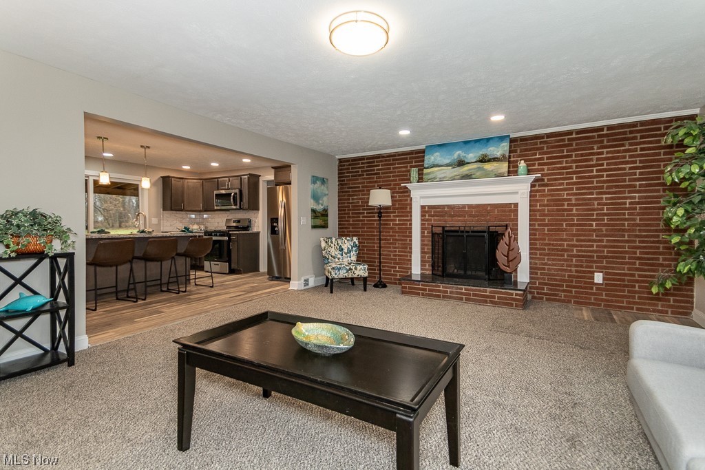 9865 Chillicothe Road Kirtland, OH 44094 - Photo 8 of 36 Living room featuring light carpet, a textured ceiling, a fireplace, and brick wall