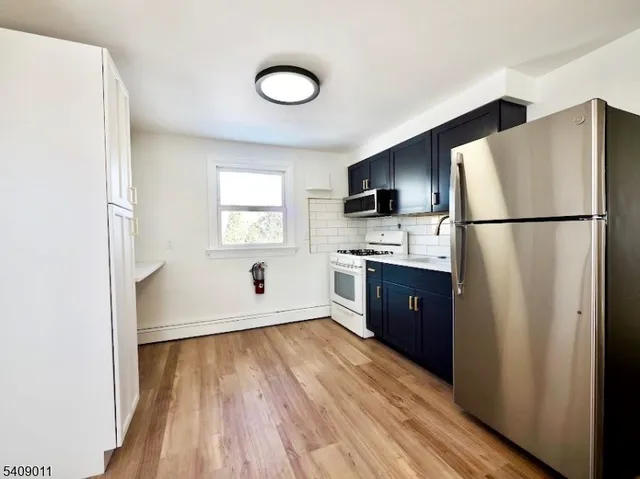 a kitchen with stainless steel appliances a refrigerator sink and wooden floor