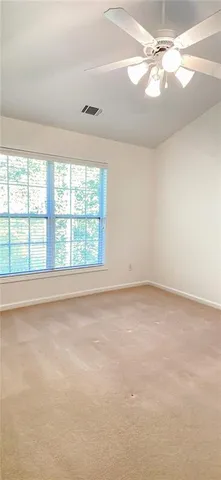 an empty room with windows and fan